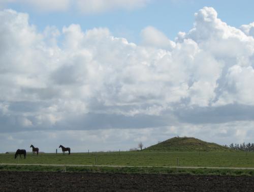 Hügelgrab mit Pferden, die in der Nähe weiden